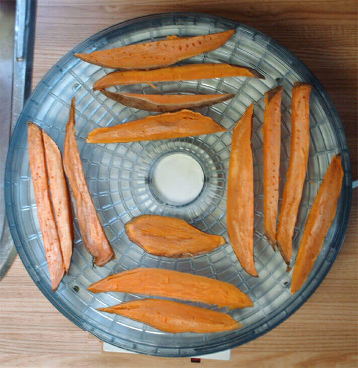 sweet potatoes cut into strips placed in a dehydrator to make treats for dogs