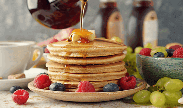 image of a stack of pancakes with someone pouring maple syrup over them