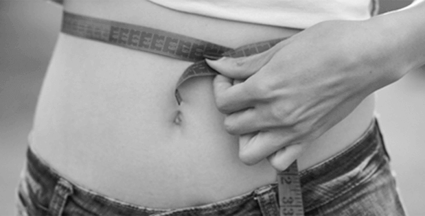 black & white image of a person's waist using a measuring tape