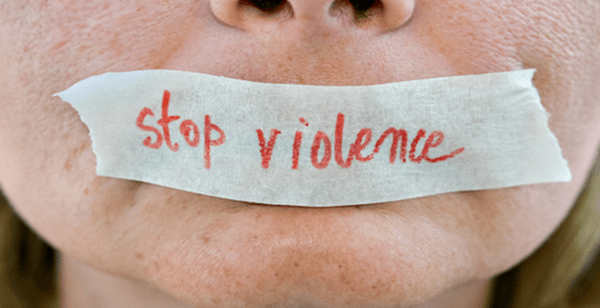 close up of a human's mouth with masking tape over top. The making tape has "stop violence" written on it.