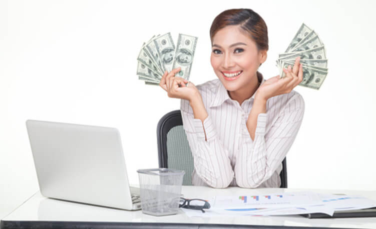 lady holding cash in her hands while sitting at her desk, in front of her laptop computer